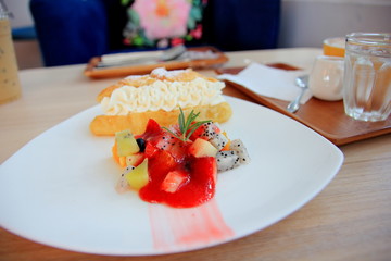 Croissant and cream with  fruit in white discon the wooden table.
