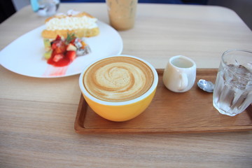 Late art in yellow cup on the brown table.Relax time with coffee.