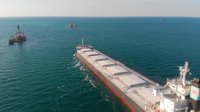 The large cargo vessel left the port after loading and moves in the right direction at high speed. Balker goes in the ocean.