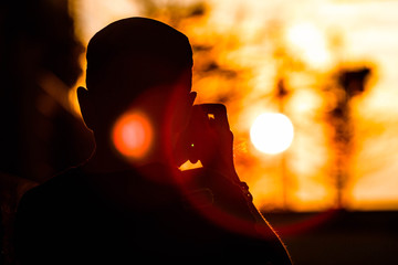 silhouette man photographing at sunset