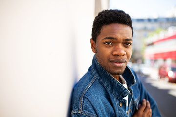 Close up side of young african american man standing outside by white wall