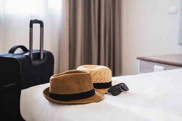 Travel luggage with hat on bed in the hotel room, Summer vacation concept