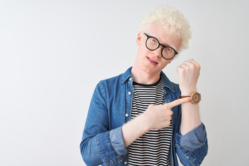 Young albino blond man wearing denim shirt and glasses over isolated white background In hurry...