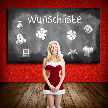 attractive blonde miss santa in front of a blackboard with a wishlist