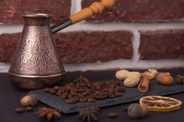 Beautiful composition of coffee beans, utensils for making coffee and decor in the form of almonds, dried slices of lemon, peanut and cinnamon on black and blue backgrounds.