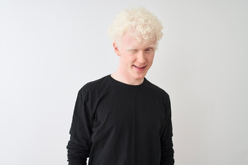 Young albino blond man wearing black t-shirt standing over isolated white background winking...