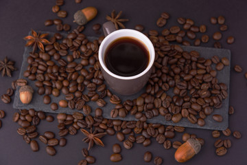 Beautiful composition of coffee beans, utensils for making coffee and decor in the form of almonds, dried slices of lemon, peanut and cinnamon on black and blue backgrounds.