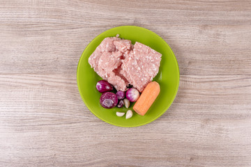 Ingredients for stuffing peppers, minced pork, onions, garlic, carrots laid out on a green plate