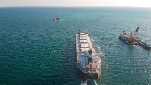 The large cargo vessel left the port after loading and moves in the right direction at high speed. Balker goes in the ocean.