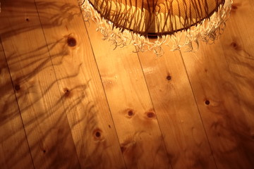 Fancy patterns of shadow and light from a lamp with a lampshade on a wooden floor