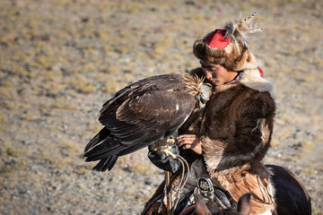 Portrait of a traditional kazakh eagle hunter with his golden eagle on horseback. Ulgii, Mongolia.