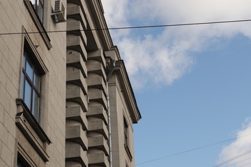 Obraz na płótnie Canvas Urban look at the sky - gray house facade and blue sky with clouds