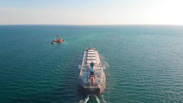The large cargo vessel left the port after loading and moves in the right direction at high speed. Balker goes in the ocean.