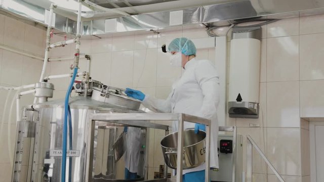 Female scientist puts ingredients into the reactor for the preparation of medicines.