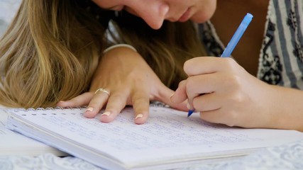 Young left handed woman writing report with pen in notebook, close up