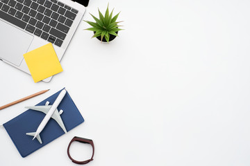 Flat lay vacation planing and traveler concept on white table background with passport and plane, sticky note and laptop computer, calendar and accessories, Top view with copy space