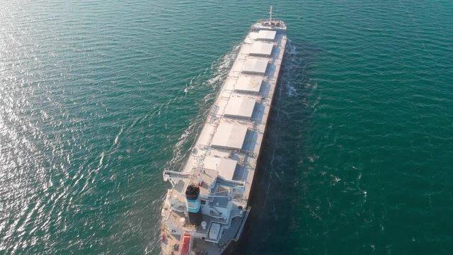 The large cargo vessel left the port after loading and moves in the right direction at high speed. Balker goes in the ocean.