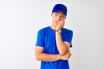 Chinese deliveryman wearing blue t-shirt and cap standing over isolated white background looking stressed and nervous with hands on mouth biting nails. Anxiety problem.