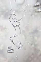 Silver curly spiral thin wrapping foils and bokeh on the background. Celebration concept