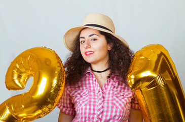 Portrait of a girl in a straw hat and with golden balloons