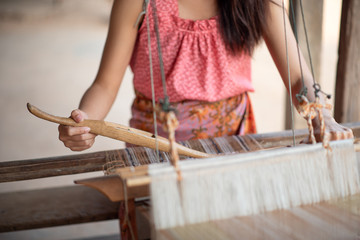 Close-up of women's hands weaving with traditional Thai weaving machine