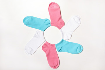 Multi-colored short socks lying in the shape of a flower on a white background. Top view