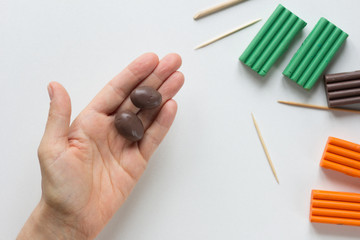 Two handmade small potatoes made from polymer clay on woman hand on white background