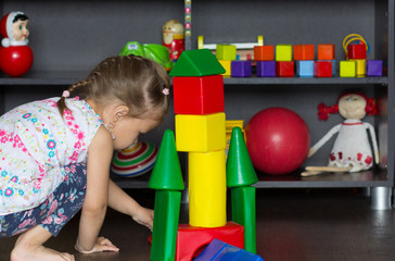 Fototapeta na wymiar Little girl playing with big multicolor plastic blocks