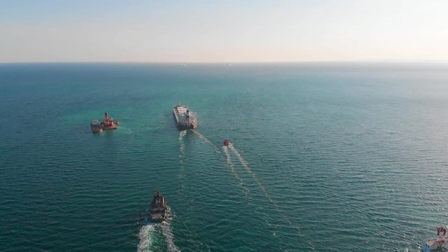 The large cargo vessel left the port after loading and moves in the right direction at high speed. Balker goes in the ocean.