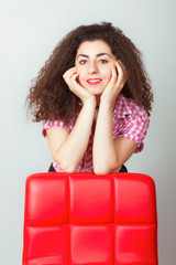 Girl with curly magnificent hair rested her elbows on a chair.