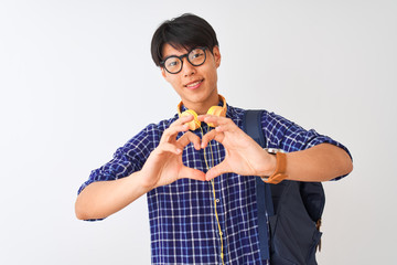 Chinese student man wearing backpack and headphones over isolated white background smiling in love showing heart symbol and shape with hands. Romantic concept.