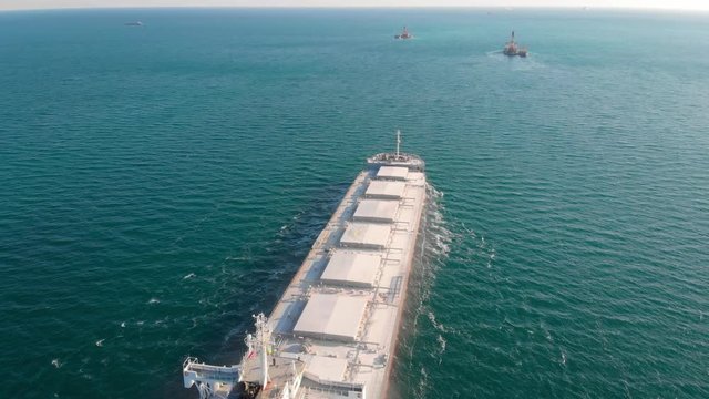 The large cargo vessel left the port after loading and moves in the right direction at high speed. Balker goes in the ocean.