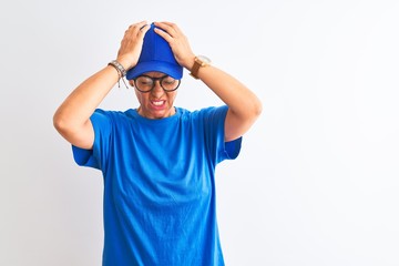Fototapeta premium Senior deliverywoman wearing cap and glasses standing over isolated white background suffering from headache desperate and stressed because pain and migraine. Hands on head.