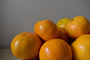 Orange fruits indoors against a white background. Satsumas, clementine fruits, sources of vitamin C.