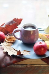 Cup of coffee on the background of the window, behind which rain, apples, a warm scarf, leaves, autumn season, the concept of home comfort