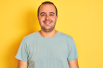 Obraz premium Young man wearing green casual t-shirt standing over isolated yellow background with a happy and cool smile on face. Lucky person.