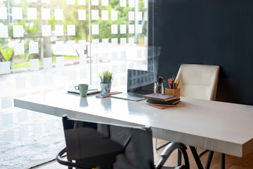 Office workplace with laptop and coffee and books and equipment on the desk.