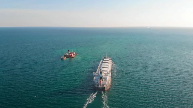The large cargo vessel left the port after loading and moves in the right direction at high speed. Balker goes in the ocean.