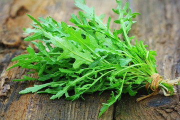 Fresh green arugula leaves on wooden rustic background . Rocket salad or rucola, healthy food, diet. Nutrition concept