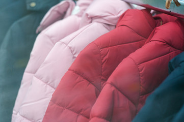 Naklejka premium Closeup of colorful winter jackets on hangers in fashion store showroom
