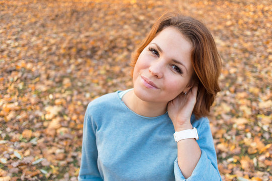 Beautiful nice girl is dreaming, posing, walking in autumn park or forest. Golden fall, colorful yellow fallen leaves. Portrait of a georgeous young woman outdoors.