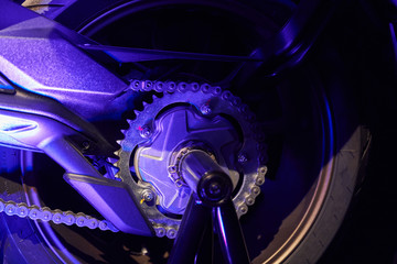 The rear wheel of a modern motorcycle with blue lighting. Studio shooting