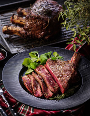 Steak on the bone. Rib eye. Tomahawk steak on the black plate with rosemary. Roasting - Rare. Entrecote
