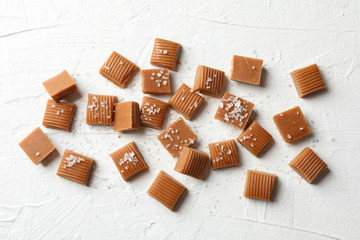 Salted caramel candies on white cement background, space for text
