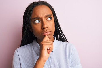 Young african american woman wearing striped shirt standing over isolated pink background serious...