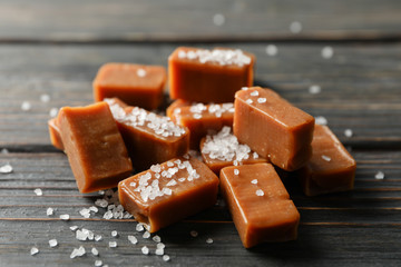 Salted caramel candies on wooden background, space for text