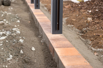 Piers on new paving stones. Preparation for the fence construction