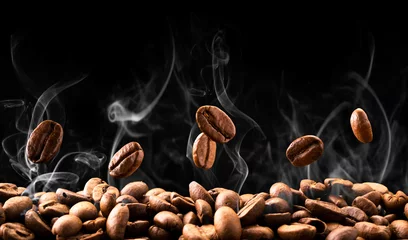 Zelfklevend Fotobehang Keuken Koffiebonen vallen in rook op een zwarte achtergrond. Koffie branden