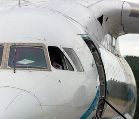 Fototapeta na wymiar Modern jet airplane on apron at airport preparing for departure closeup front view of passenger aircraft parked with pilot in cockpit and technical maintenance staff on tarmac.