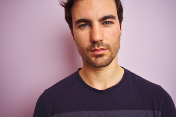 Young handsome man wearing casual t-shirt standing over isolated pink background with a confident expression on smart face thinking serious